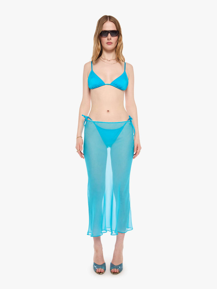 Full body view of a woman in a string bikini top from SPRWMN designed in turquoise with a triangle design and tie closures.