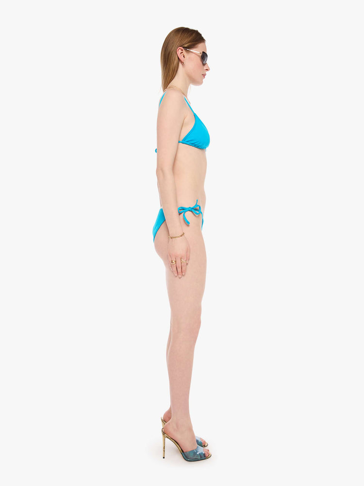 Side view of a woman in a string bikini bottom from SPRWMN designed in turquoise with a high rise and tie closures.
