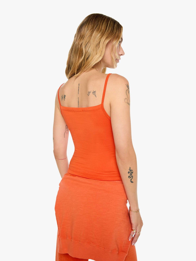 Back view of a woman in papaya orange tank designed with thin spaghetti straps, a scoop neck and cropped fit.