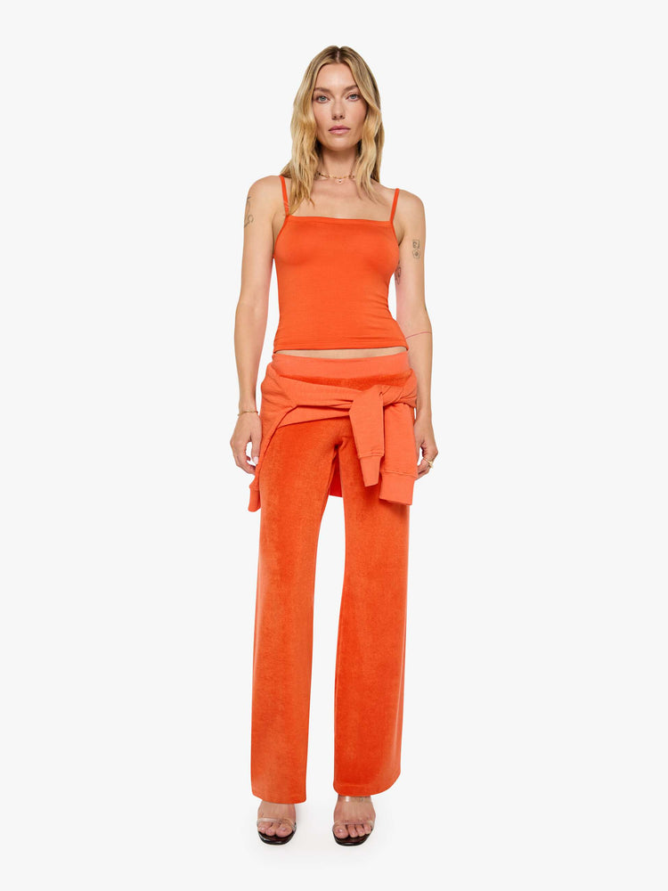 Full body view of a woman in papaya orange tank designed with thin spaghetti straps, a scoop neck and cropped fit.
