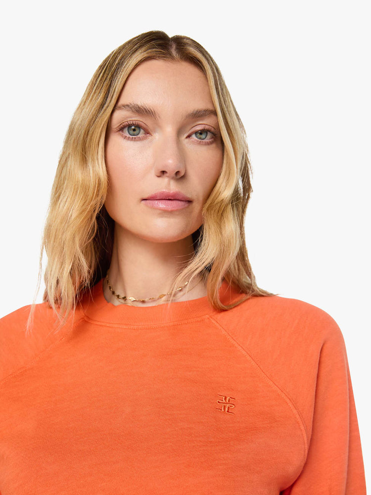 Close up view of a woman in a  papaya orange raglan sweatshirt is designed with a crewneck, ribbed hems and a cozy fit.