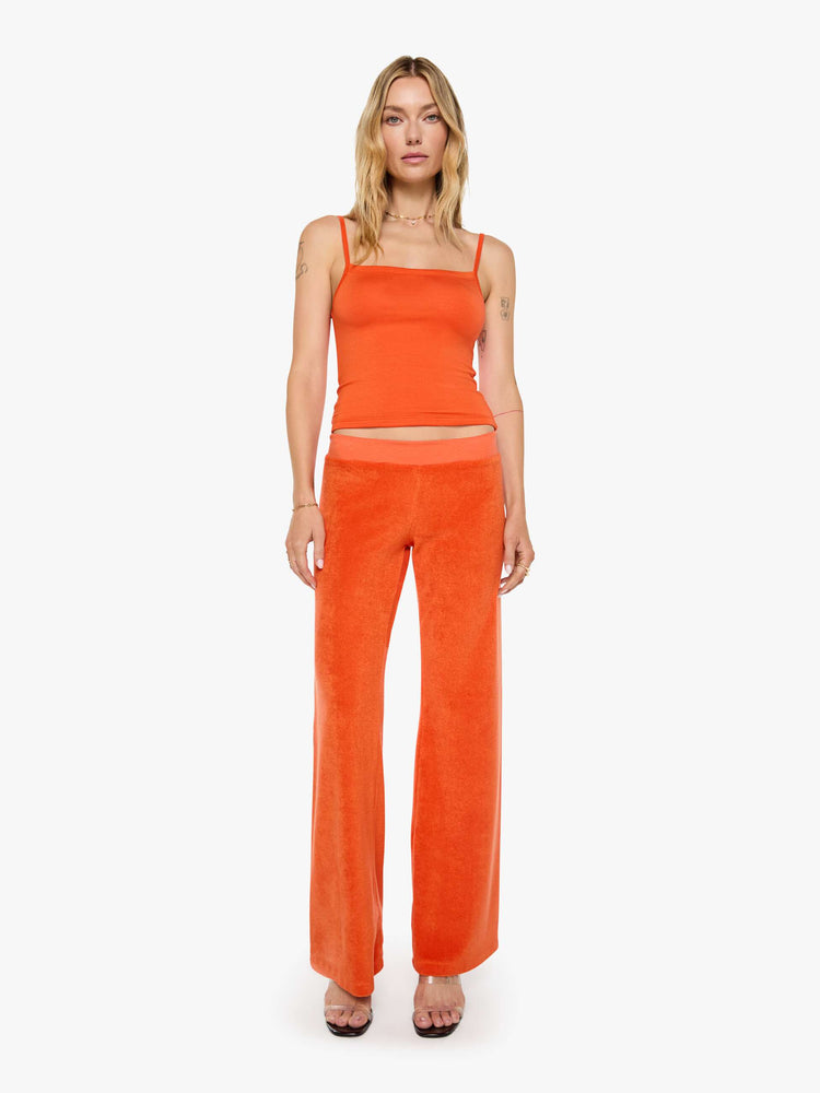 Front view of a woman in a papaya orange pants with a low rise, elastic waistband, loose leg and a cozy fit.