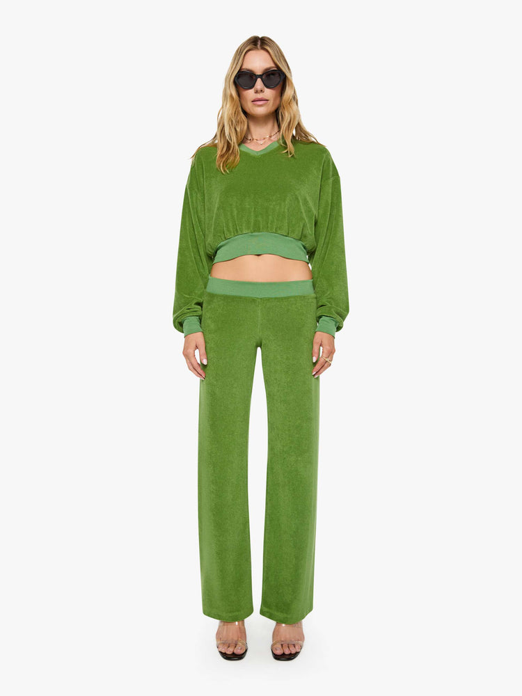 Full body view of a woman in a green sweatshirt is designed with a short V-neck, drop shoulders, ribbed hems and a cropped, cozy fit.