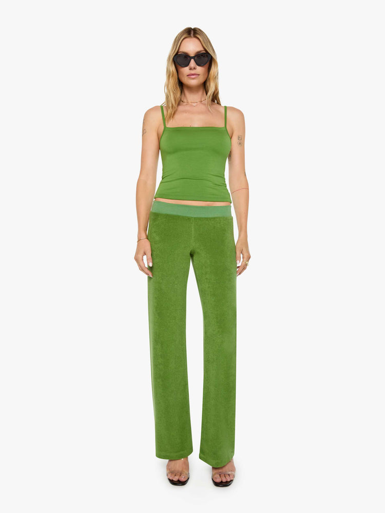 Front view of a woman in a green pants have a low rise, elastic waistband, loose leg and a cozy fit.
