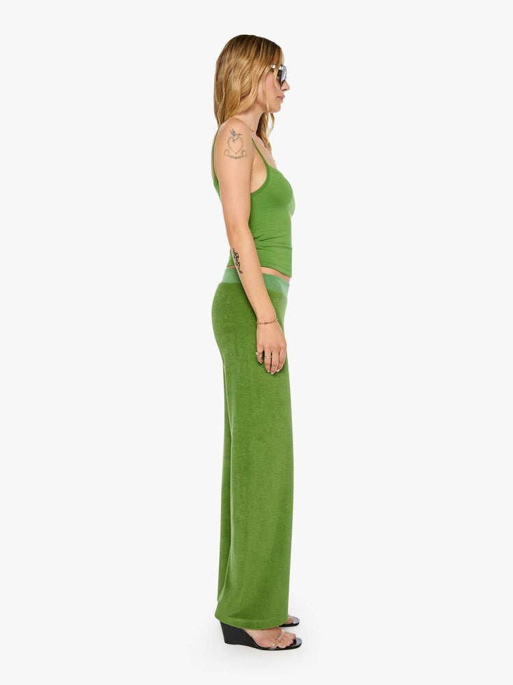 Side view of a woman in a green pants have a low rise, elastic waistband, loose leg and a cozy fit.
