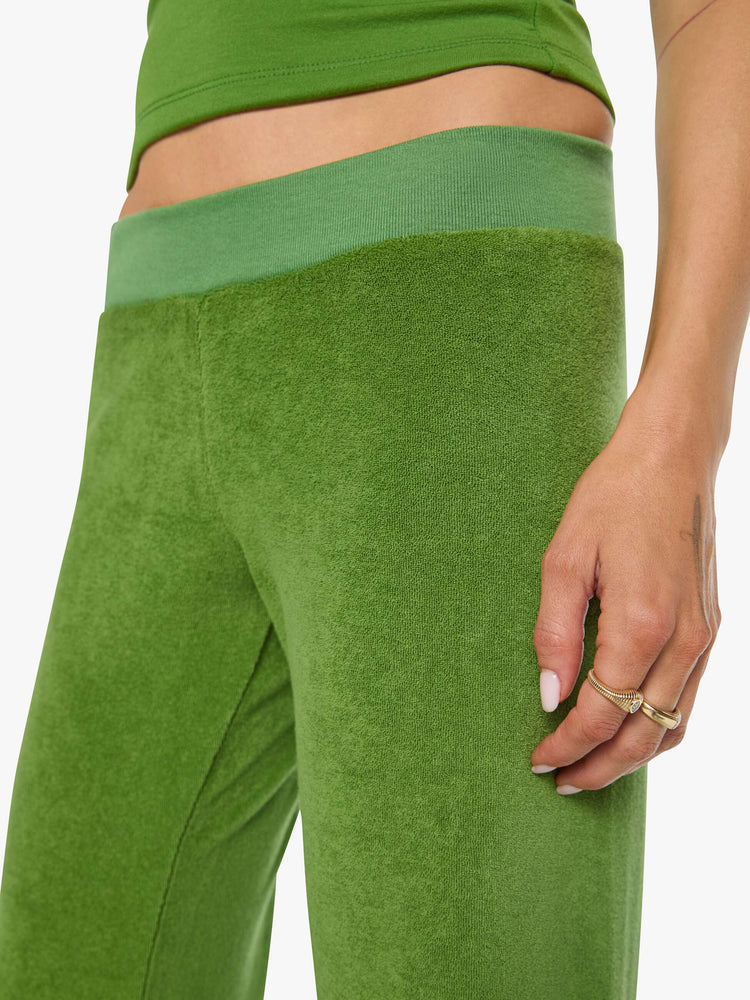 Close up view of a woman in a green pants have a low rise, elastic waistband, loose leg and a cozy fit.