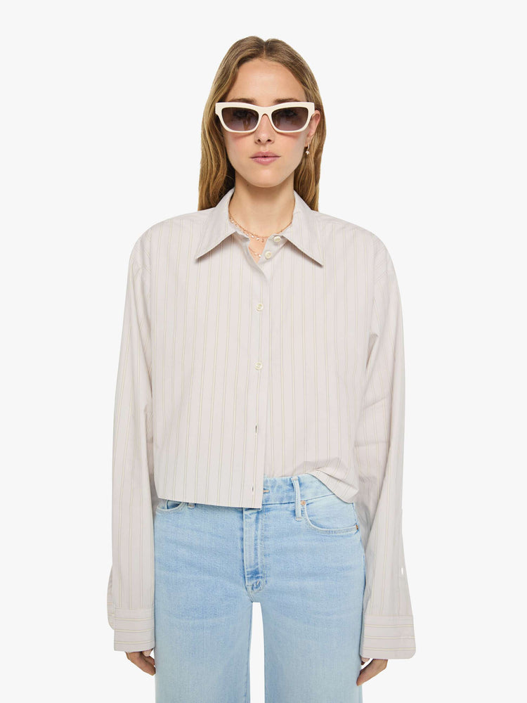 Front view of a woman in a grey with cream stripes button up top designed with a cropped, boxy fit. 