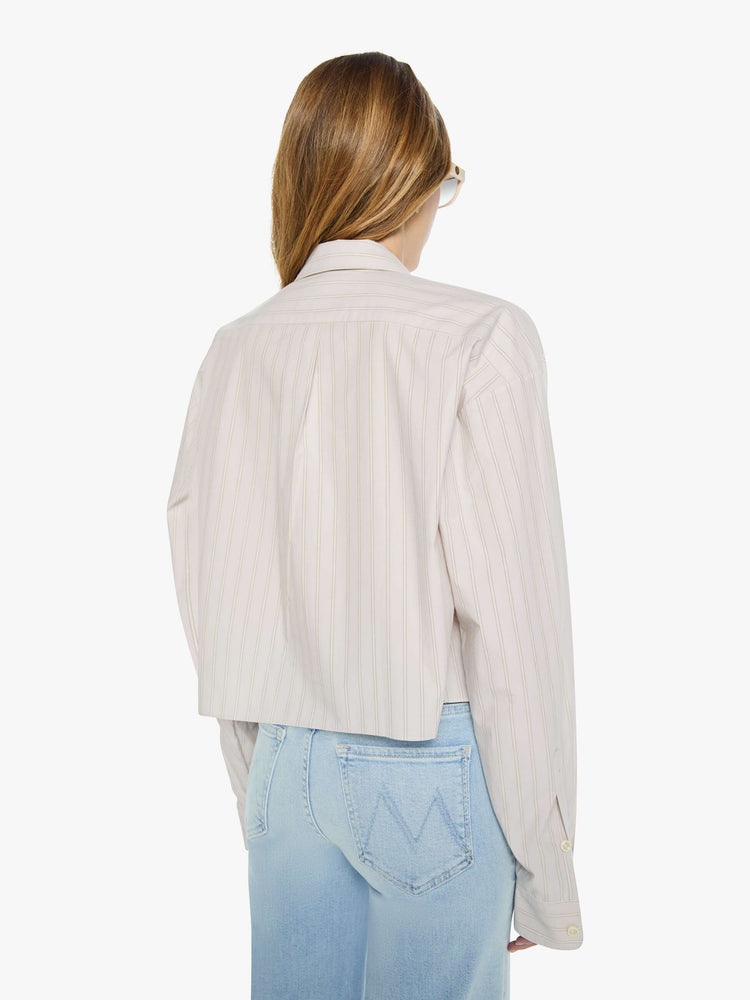 Back view of a woman in a grey with cream stripes button up top designed with a cropped, boxy fit. 