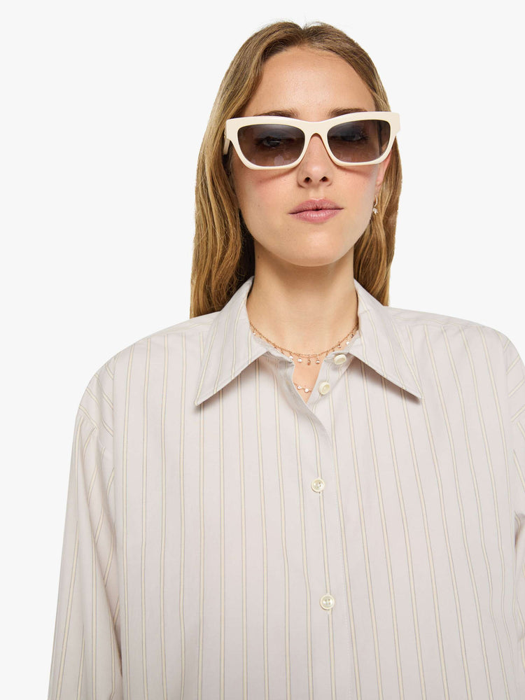 Close up view of a woman in a grey with cream stripes button up top designed with a cropped, boxy fit. 