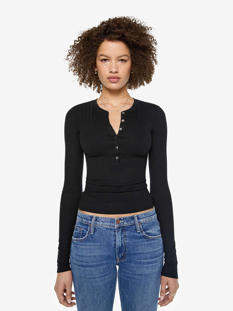 Front view of a woman in a  black with white buttons, the top is designed with a buttoned V-neck, long sleeves and a narrow fit.