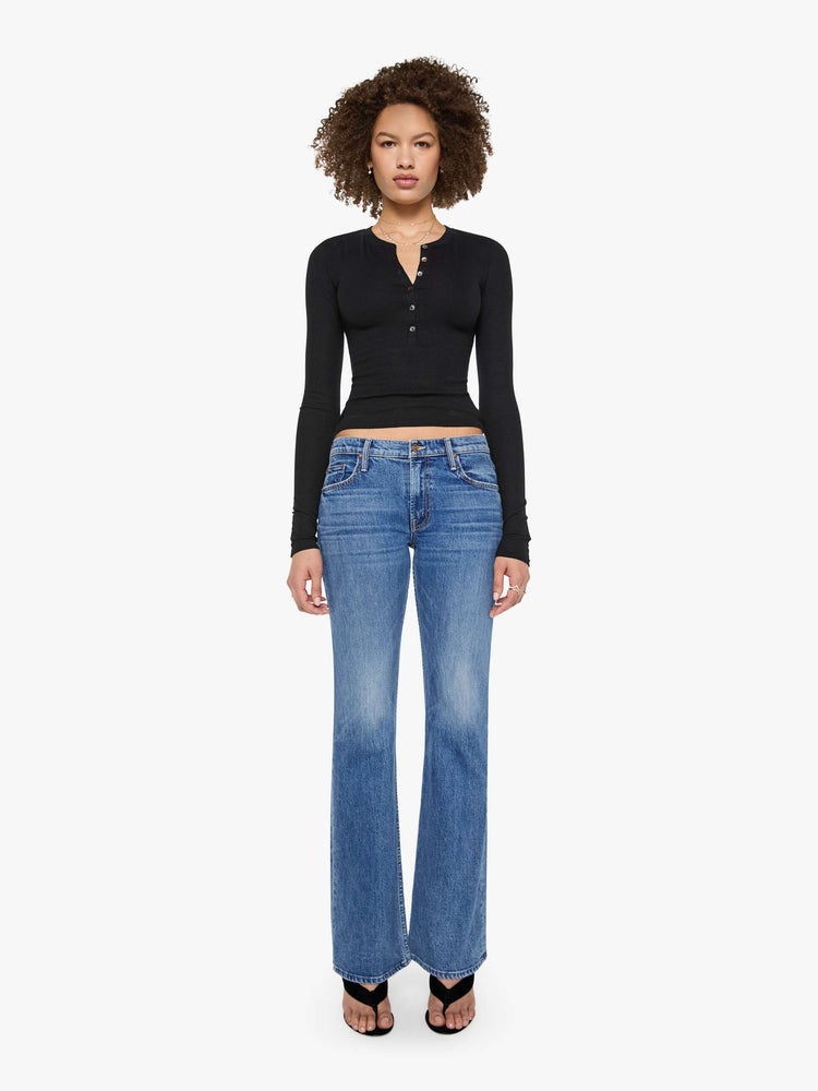 Full body view of a woman in a  black with white buttons, the top is designed with a buttoned V-neck, long sleeves and a narrow fit.