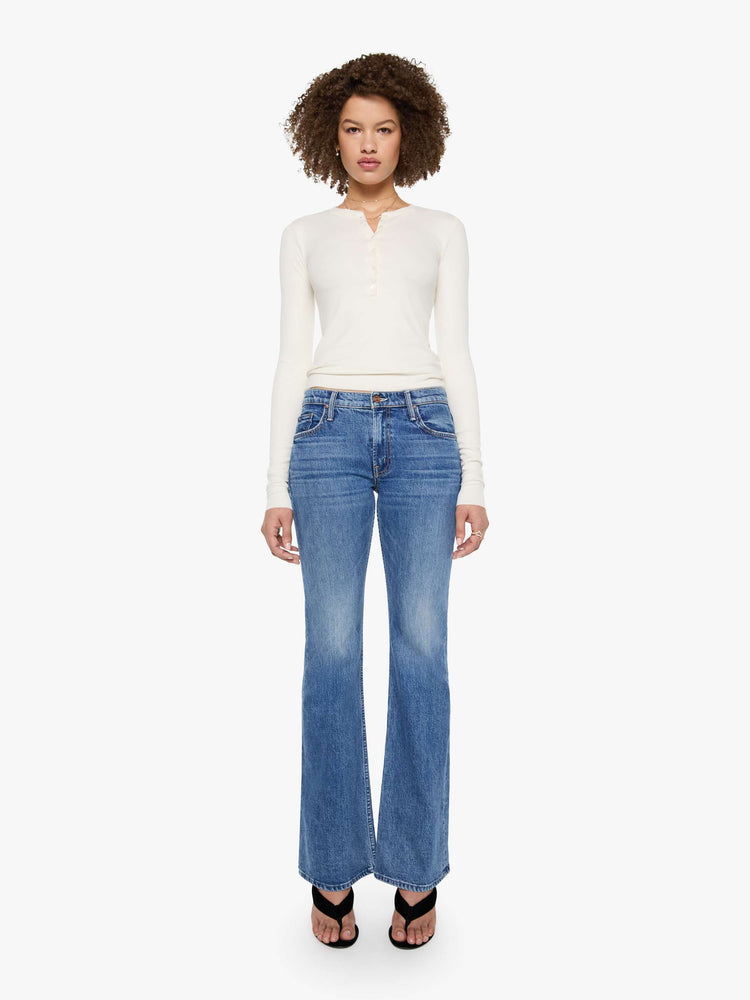 Full body view of a woman in a cream with tonal buttons, the top is designed with a buttoned V-neck, long sleeves and a narrow fit.