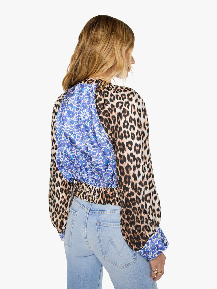 Back view of a woman in blue and white floral print with cheetah print trim and sleeves shirt with a crewneck, long balloon sleeves and a slightly cropped fit.