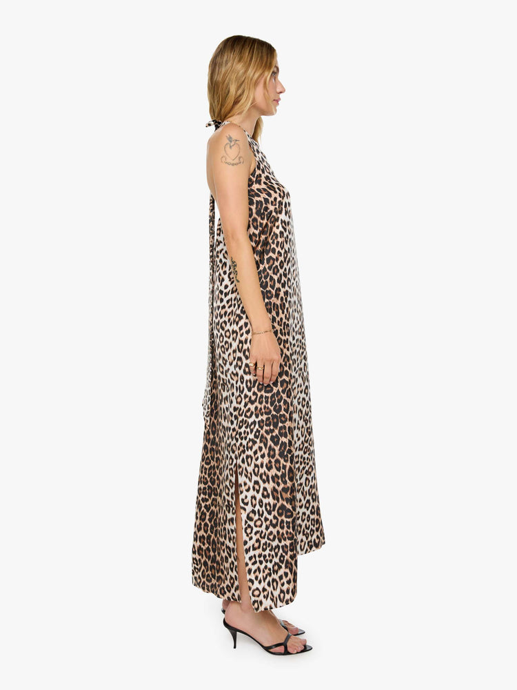 Side view of a woman in cheetah print dress with a halter neck, ankle-length hem and a loose, flowy fit.