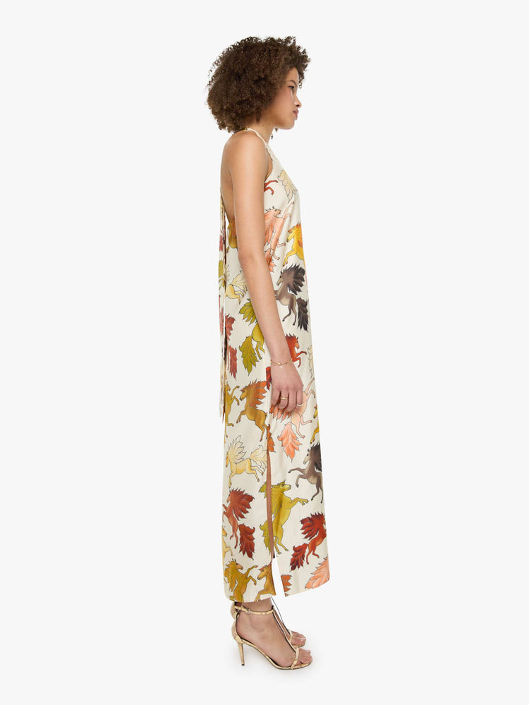 Side view of a woman in prints with classic silhouettes, featuring a high halter neck, semi-fitted waist and a flowy ankle-length skirt.