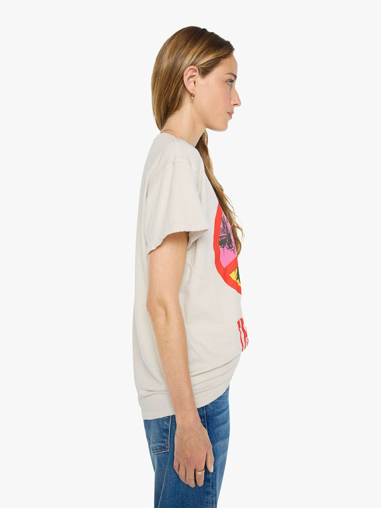Side view of a woman in vintage white tee pays homage to The Beatles with a red peace sign and graphic portraits on the front.