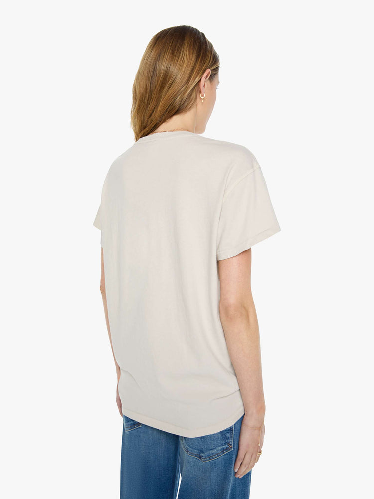 Back view of a woman in vintage white tee pays homage to The Beatles with a red peace sign and graphic portraits on the front.