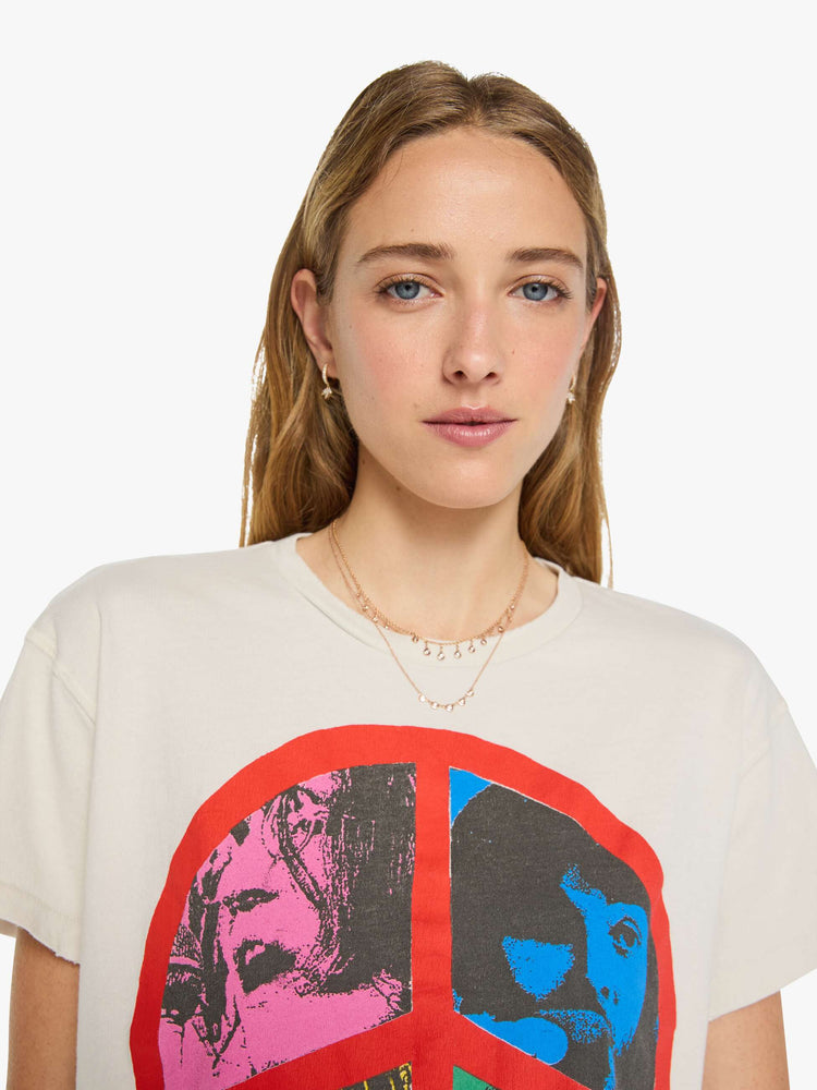 Close up view of a woman in vintage white tee pays homage to The Beatles with a red peace sign and graphic portraits on the front.