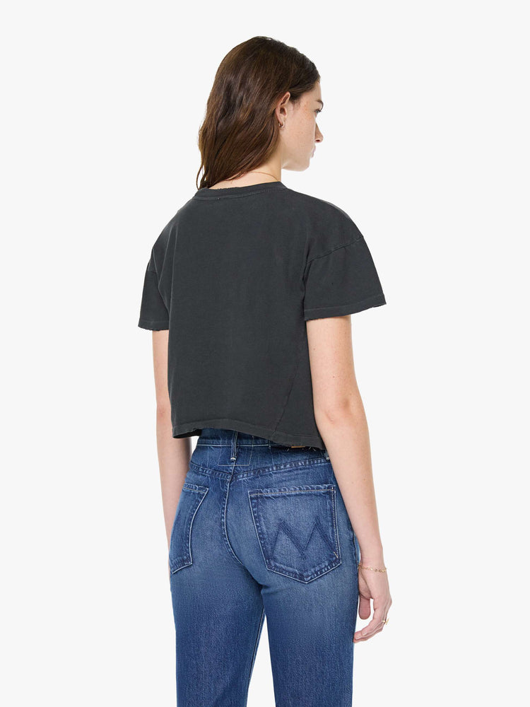 Back view of a woman in a black tee pays homage to Ozzy Osbourne with a colorful graphic and text in red and yellow on the front.