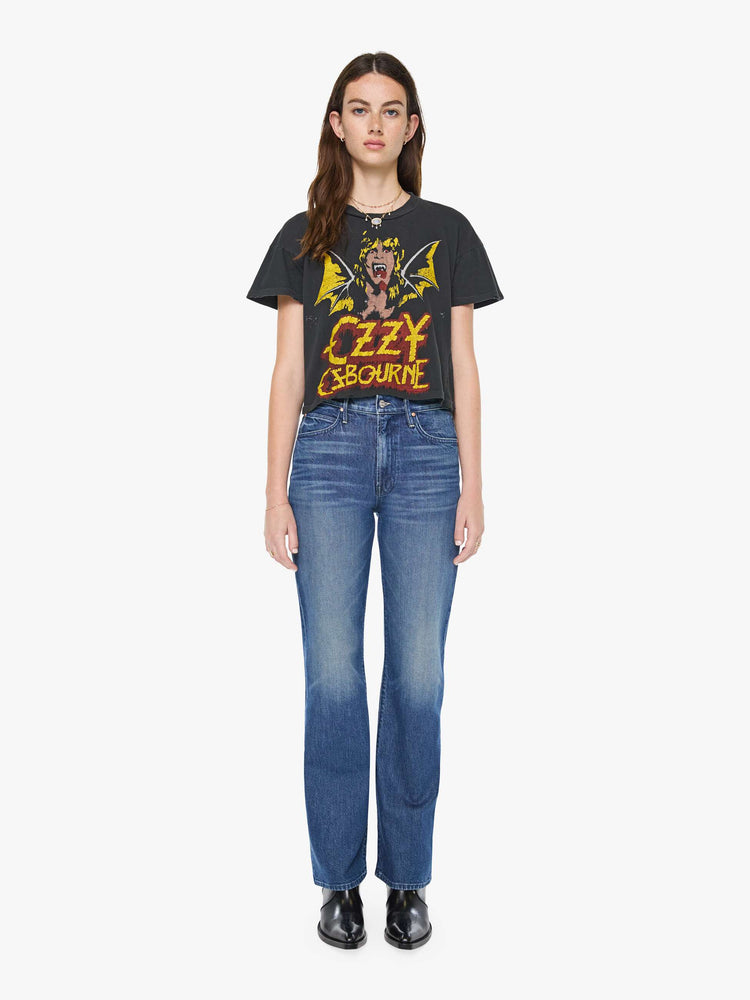 Full body view of a woman in a black tee pays homage to Ozzy Osbourne with a colorful graphic and text in red and yellow on the front.
