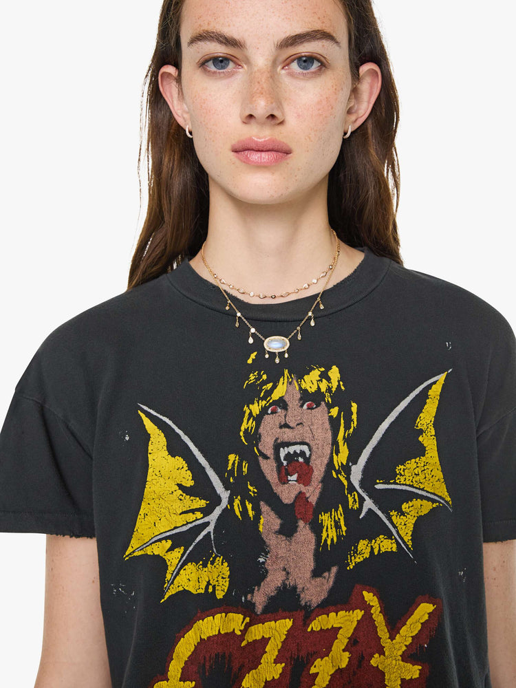 Close up view of a woman in a black tee pays homage to Ozzy Osbourne with a colorful graphic and text in red and yellow on the front.