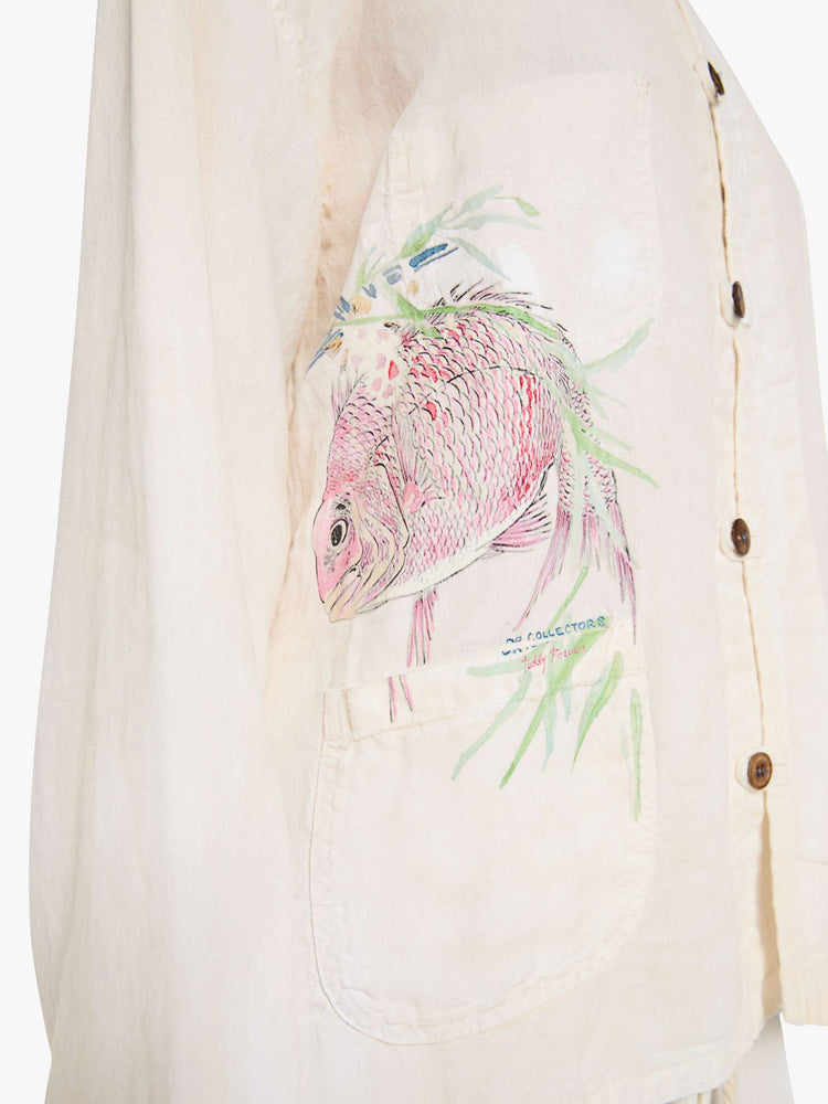 Close up view of a woman in a white jacket with a hand-drawn koi fish screen-printed on the right chest, the button-up jacket has patch pockets, dropped shoulders and a relaxed fit.