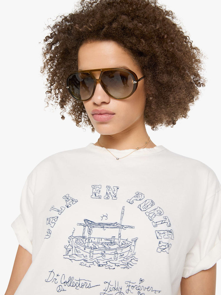 Close up view of a woman in a white tee with a scene from Menorca, Spain, in faded blue.