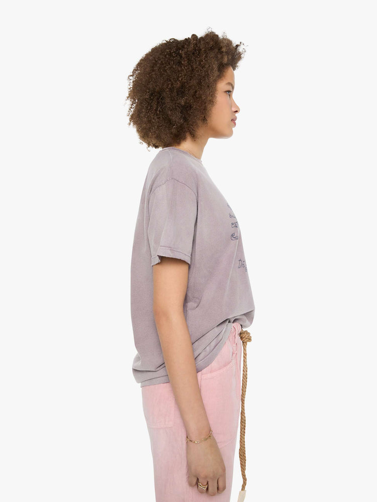 Side view of a woman in a dusty orchid tee with a scene from Menorca, Spain, in faded blue.