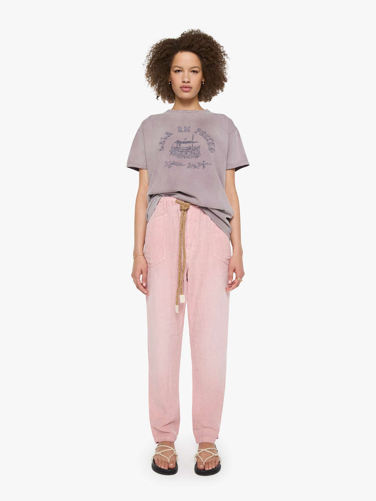 Full body view of a woman in a dusty orchid tee with a scene from Menorca, Spain, in faded blue.
