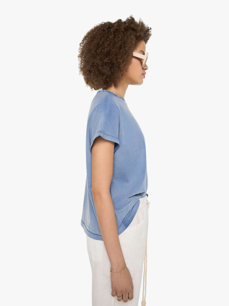 Side view of a woman in a sun-faded blue  tee with a colorful chain-stitched hummingbird and text on the back left shoulder.