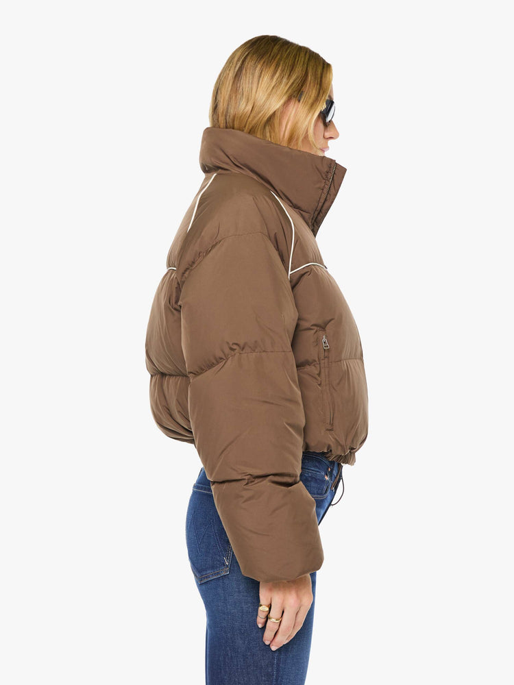 Side view of a woman in brown with cream piping jacket has a high neck, front zip pockets, elastic hems and a cropped fit.