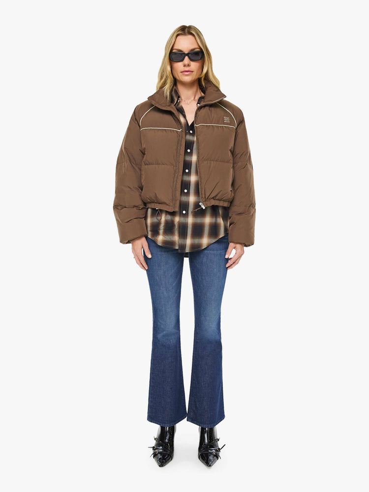 Full body view of a woman in brown with cream piping jacket has a high neck, front zip pockets, elastic hems and a cropped fit.