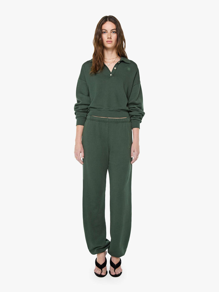 Full body view of a woman in a forest green polo sweatshirt with a buttoned V-neck, drop shoulders, long sleeves and a cropped fit.