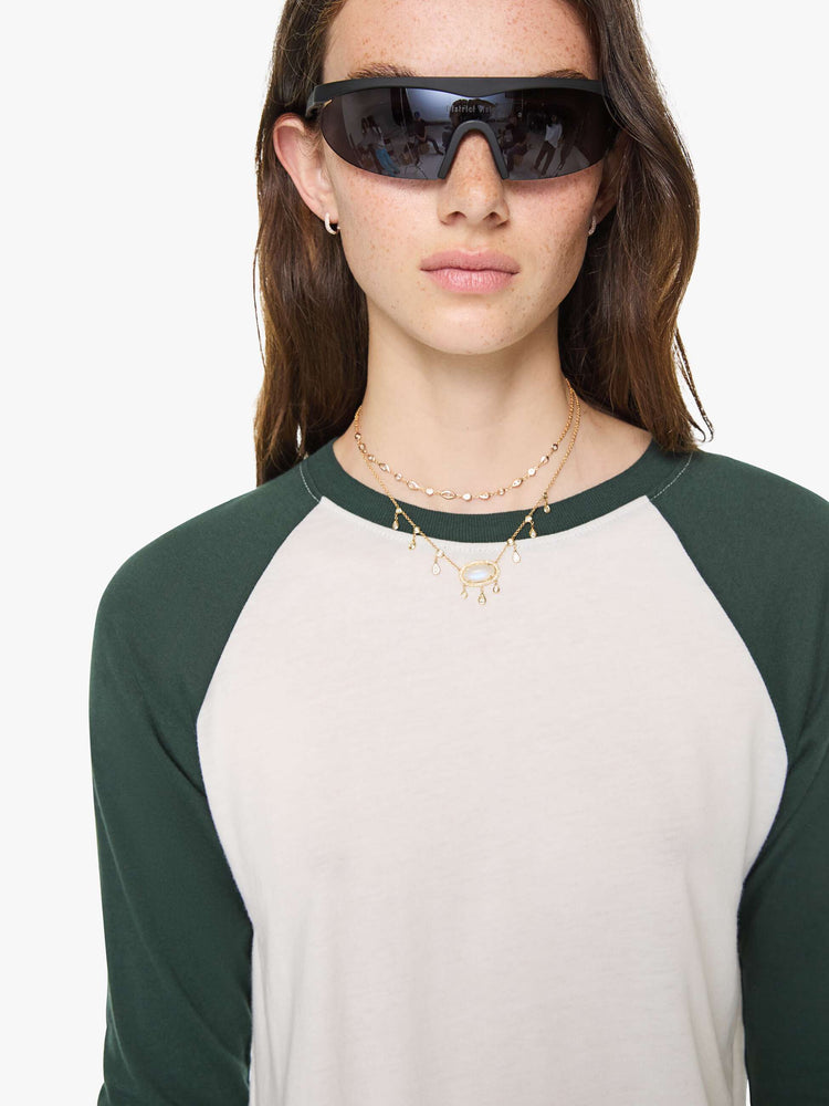 Close up view of a woman in white with forest green sleeves and trim tee is designed with a crew neck, long sleeves and a narrow, slightly cropped fit.