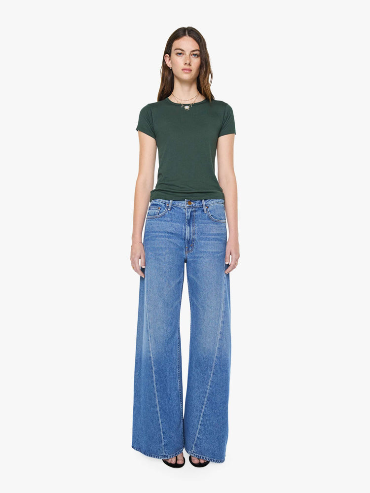 Full body view of a woman in a forest green crewneck tee is designed with short sleeves and a narrow fit.