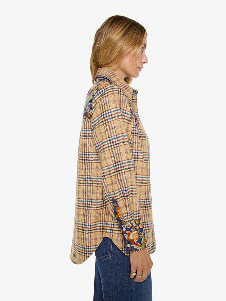 Side view of a woman in a jacket is made from 100% wool in yellow and blue plaid with floral-print panels at the chest and wrists, and features a collared neck and slightly dropped shoulders.