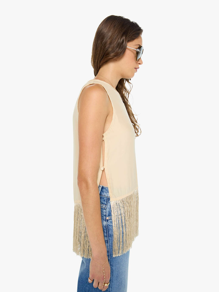 Side view of a woman in a top has a crew neck, side slits and a loose, cropped fit with long fringe at the hem.
