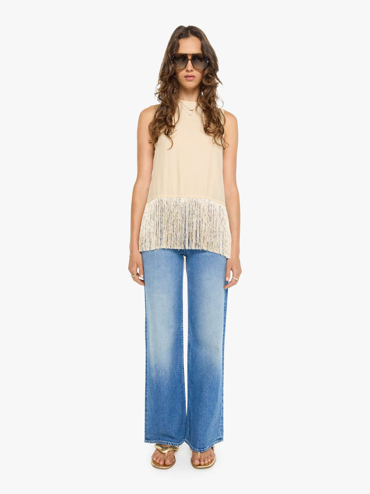 Full body view of a woman in a top has a crew neck, side slits and a loose, cropped fit with long fringe at the hem.