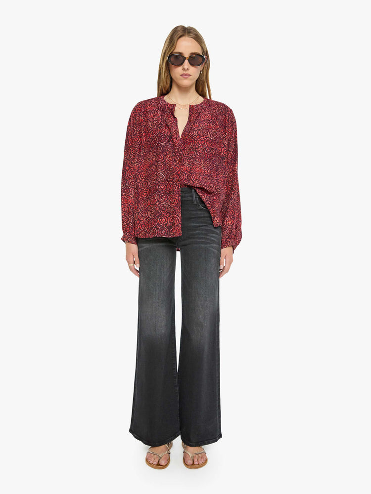 Full body view of a woman deep red shirt with a floral print, and features a crewneck, long balloon sleeves and ruffles throughout for a flowy fit.