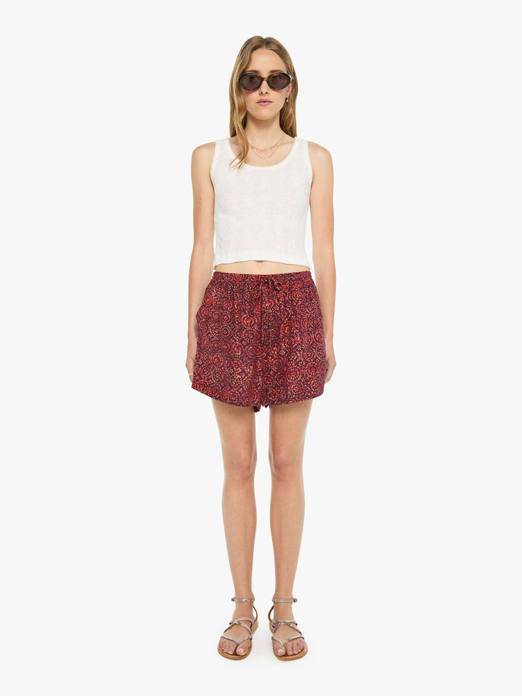 Front view of a woman in a deep red with a floral print shorts are designed with an elastic waist, side slit pockets, a slightly curved hem and a loose, flowy fit.