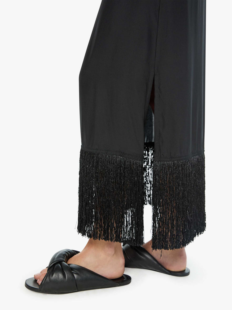Close up view of a woman in black skirt has a high rise, fringed, calf-length hem and a loose, flowy fit.