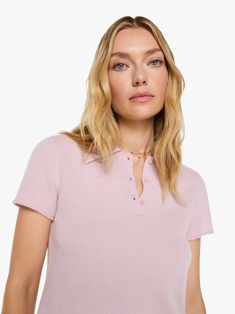 Close up view of a woman in pale pink top is designed with short sleeves, a collared V-neck that buttons and a boxy fit.