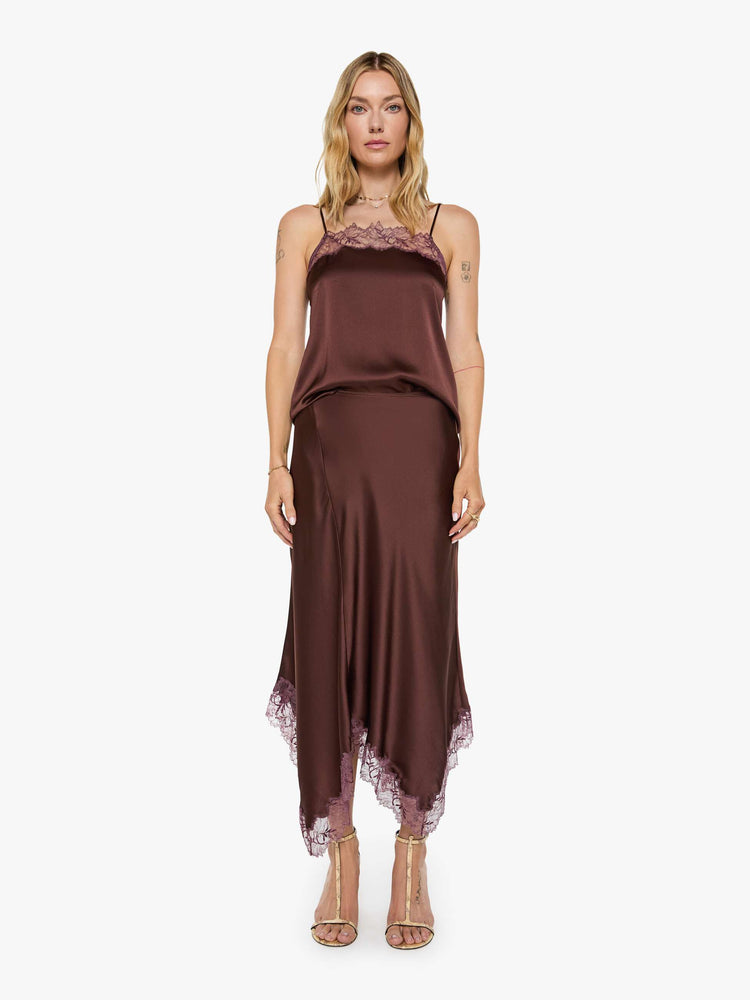 Front view of a woman in a silk in a chocolate brown with lace trim, the maxi skirt is designed with a flowy fit and an uneven, ankle-grazing hem.