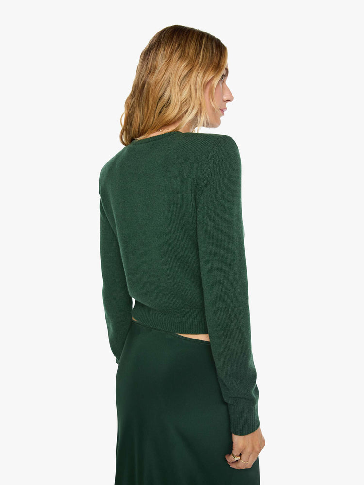 Back view of a woman in green cardigan is designed with a crewneck, long sleeves, ribbed hems and a cropped fit.
