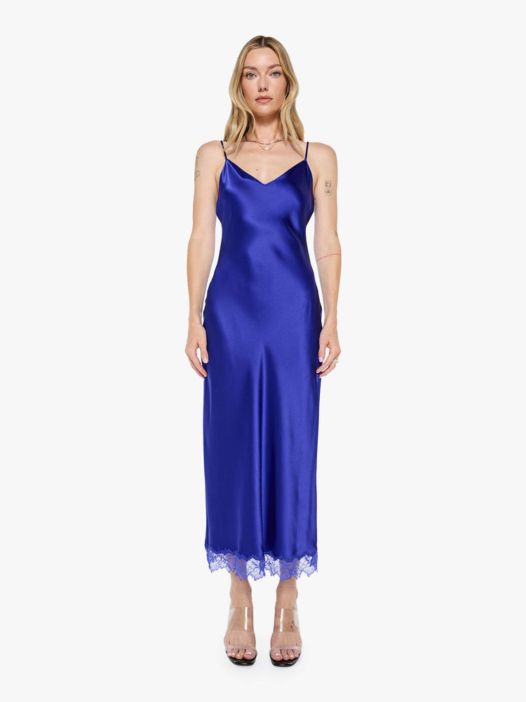 Front view of a woman in a slip cobalt blue dress is designed with thin spaghetti straps, a V-neck, lace trim, an ankle-length hem and a loose, flowy fit.