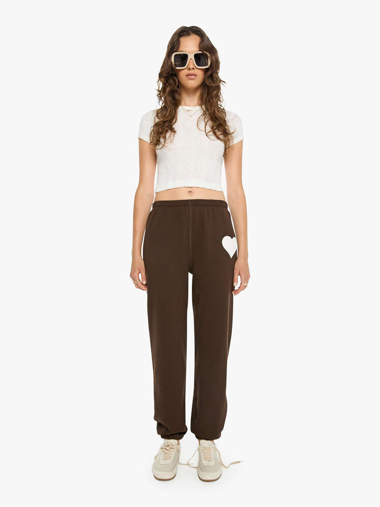 Front view of a woman in brown with white heart at the hip sweatpants have an elastic waist and cuffs for a loose, comfortable fit.
