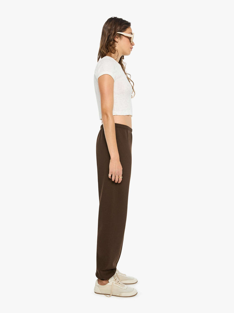 Side view of a woman in brown with white heart at the hip sweatpants have an elastic waist and cuffs for a loose, comfortable fit.