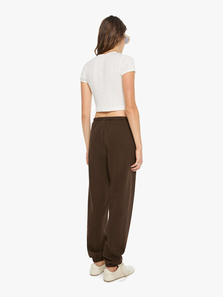Back view of a woman in brown with white heart at the hip sweatpants have an elastic waist and cuffs for a loose, comfortable fit.