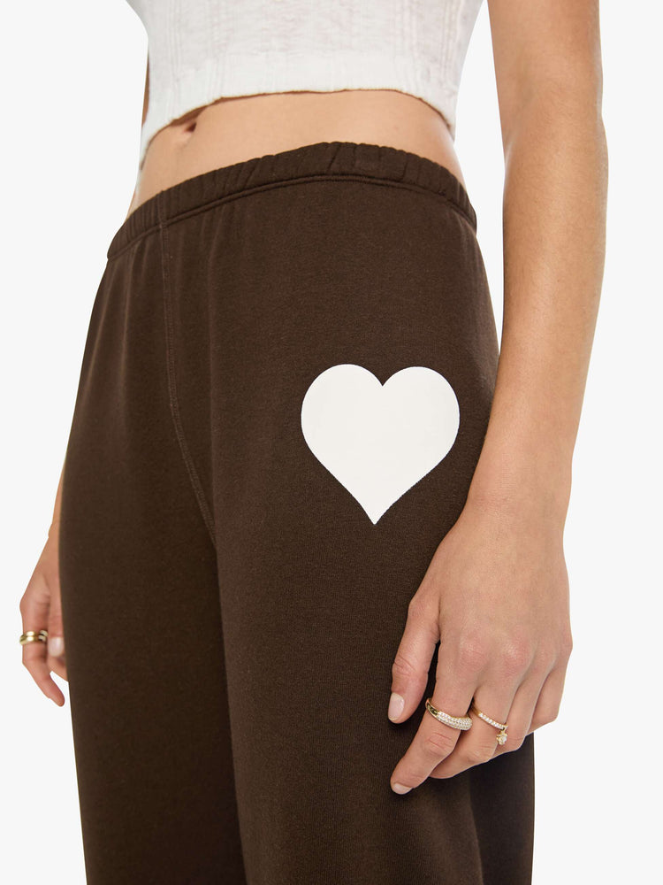 Close up view of a woman in brown with white heart at the hip sweatpants have an elastic waist and cuffs for a loose, comfortable fit.