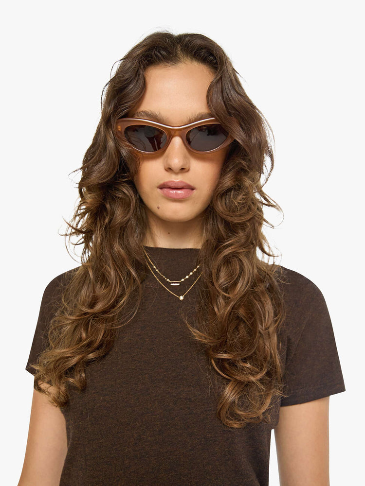 Close up view of a woman in a brown baby tee from SPRWMN with a hip-length hem, short sleeves and a semi-fitted shape.